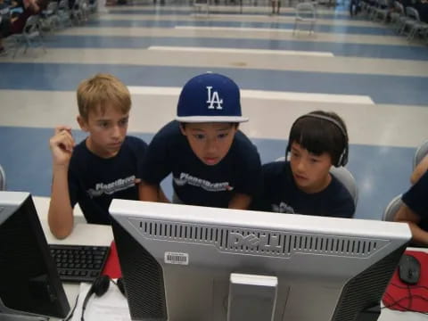 a group of boys sitting at a table with a laptop