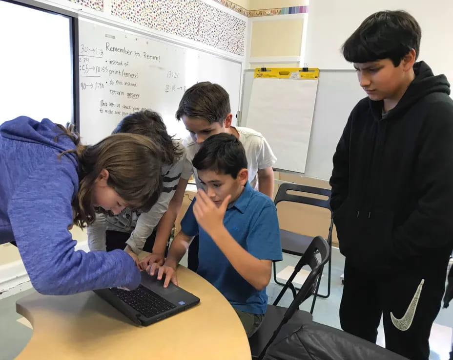 a group of people looking at a laptop