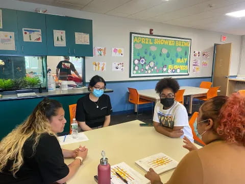 a group of people sitting at a table with masks on