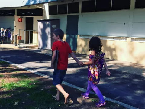 a boy and girl walking outside a building