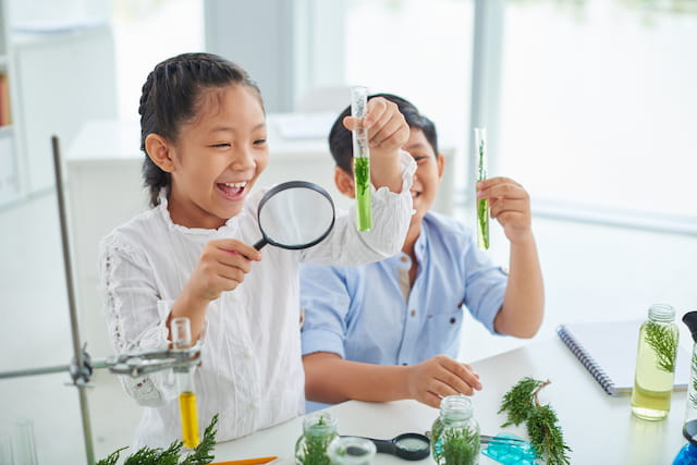 a couple of young girls holding a magnifying glass