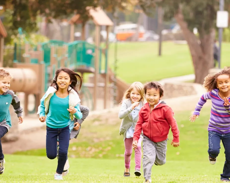 a group of children running on a grass field