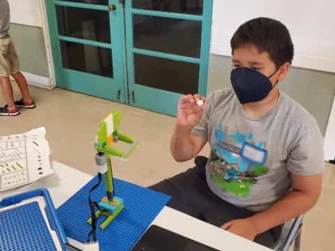 a boy wearing headphones and sitting at a table with a toy