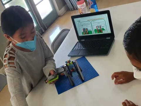 a couple of boys playing with a laptop on a table