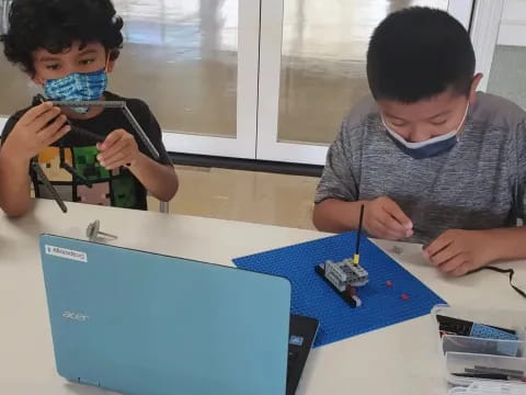 a person and a boy sitting at a table with a blue board