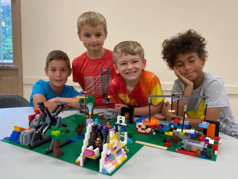 a group of boys sitting at a table with a toy building