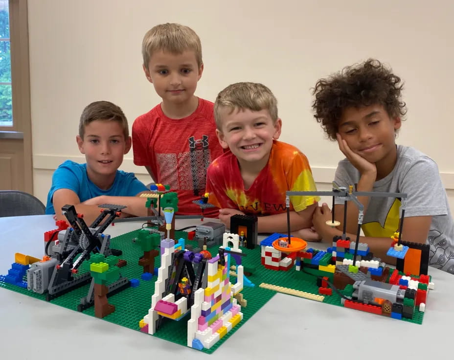 a group of boys sitting at a table with a toy building