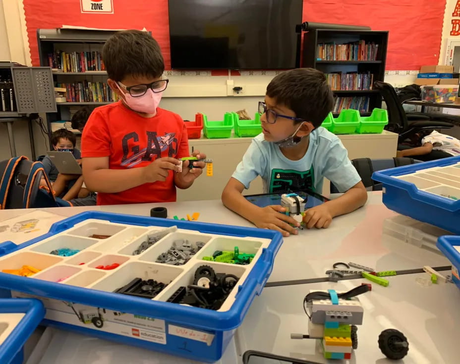 a couple of boys wearing safety goggles and looking at a blue object