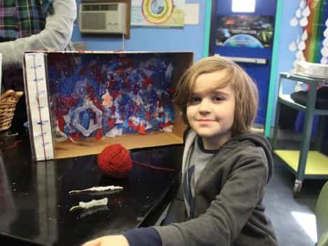 a girl sitting at a table with a computer