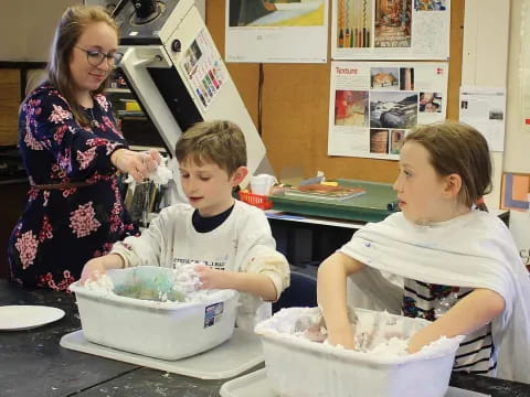 a person and a couple of kids sitting at a table with food