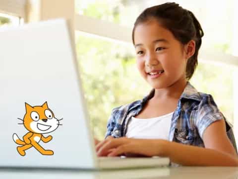 a young girl smiling at a computer