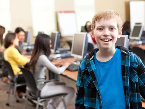 a boy smiling in front of a computer