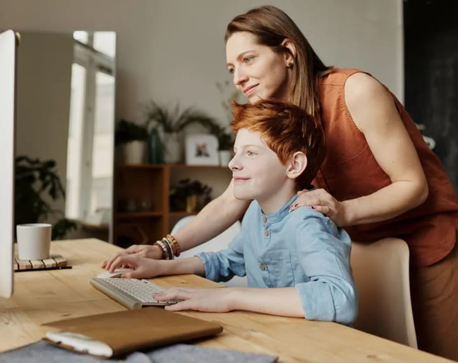 a woman and a child looking at a computer