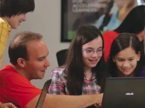 a group of people looking at a laptop