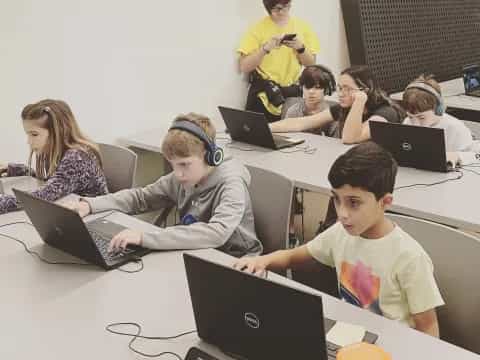 a group of children using laptops