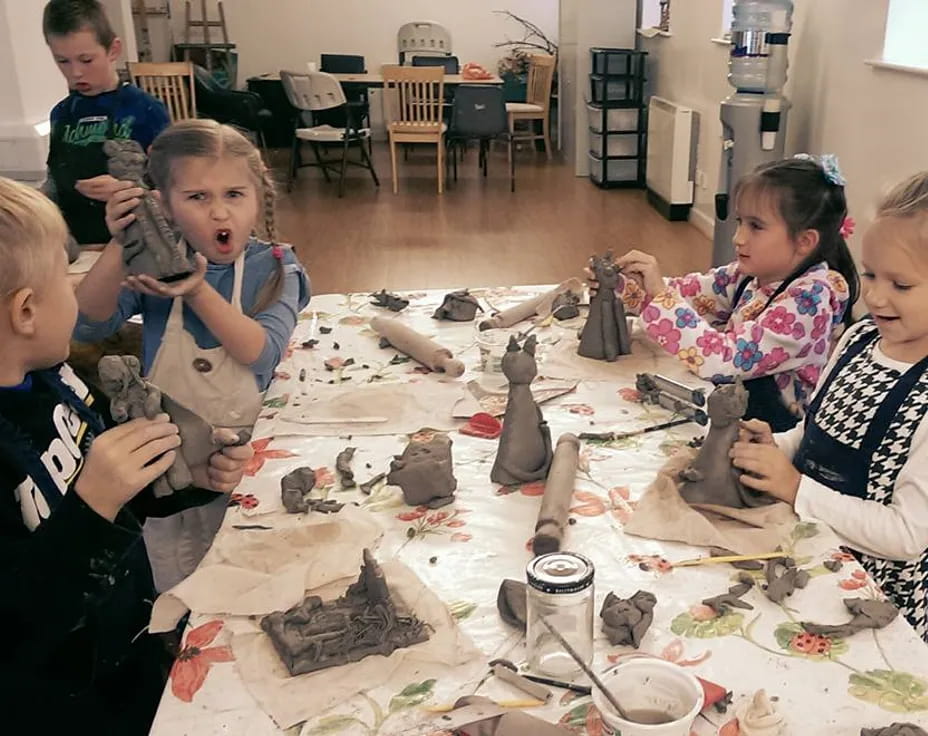 a group of children sitting around a table with objects on it