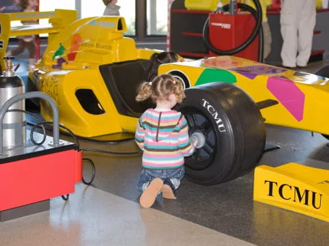 a child standing next to a toy car