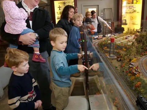 a group of people looking at a model train track