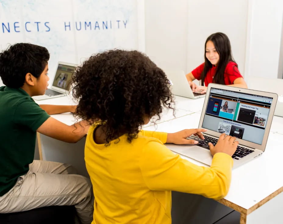 a group of people sitting at a table looking at a laptop