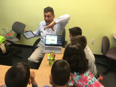 a man standing in front of a table with a group of kids