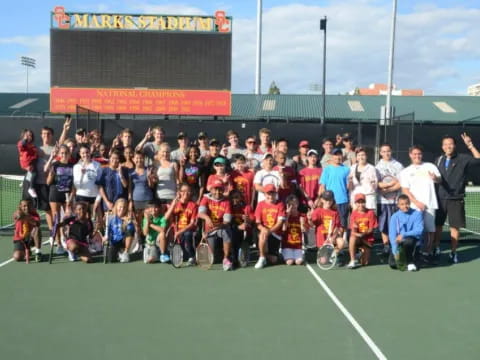 a group of people posing for a photo on a tennis court