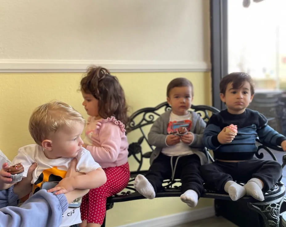 a group of children sitting on a bench eating