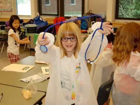 a group of girls wearing white lab coats and blue gloves