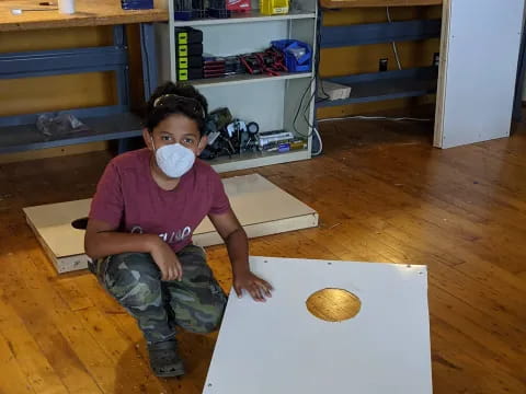 a person with a mask on the face sitting on a white box