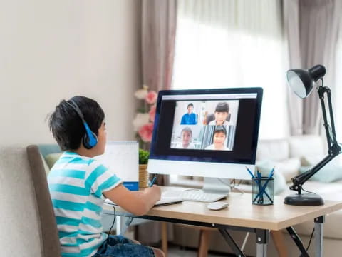 a boy sitting at a desk with a computer and headphones on