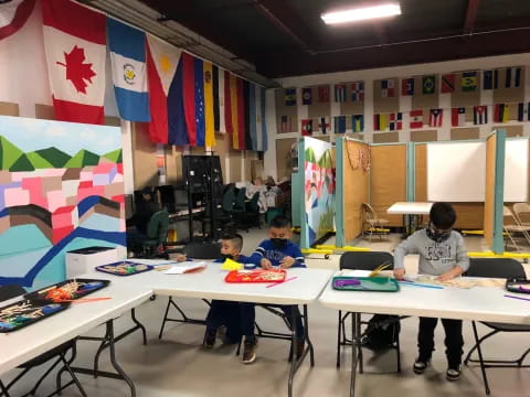 a group of people sitting at tables with laptops and flags