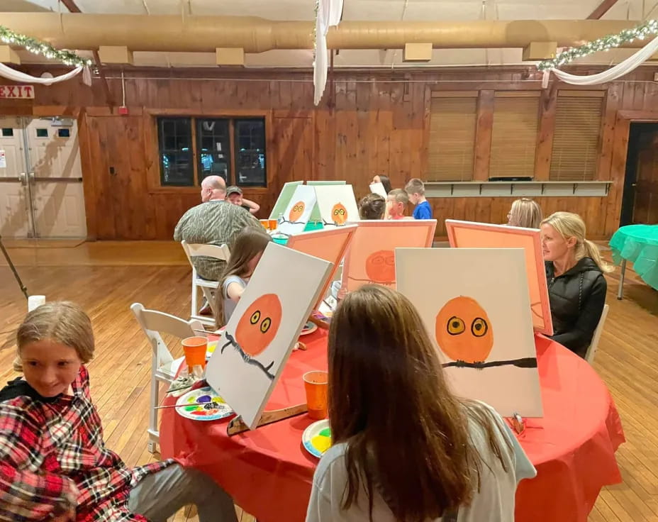 a group of people sitting at a table with a large red tablecloth