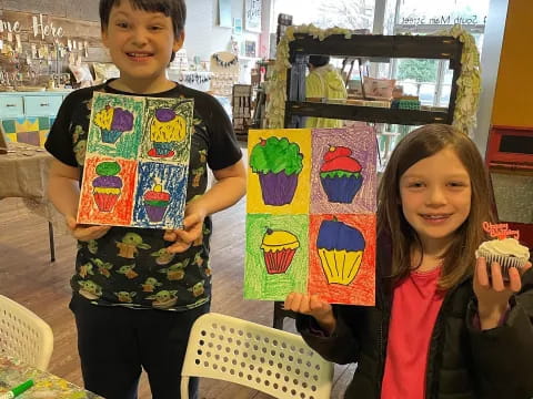 a boy and girl holding up a colorful piece of paper