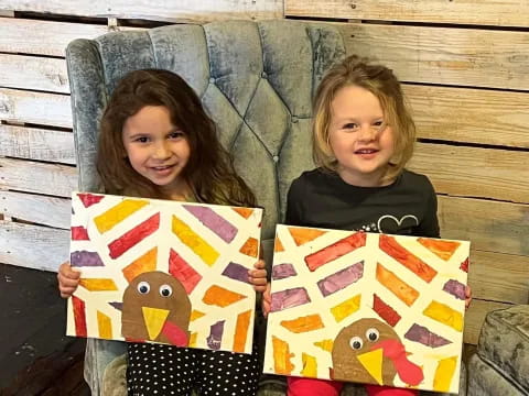 two girls holding up paintings
