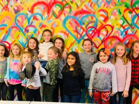 a group of children posing for a photo in front of a colorful wall