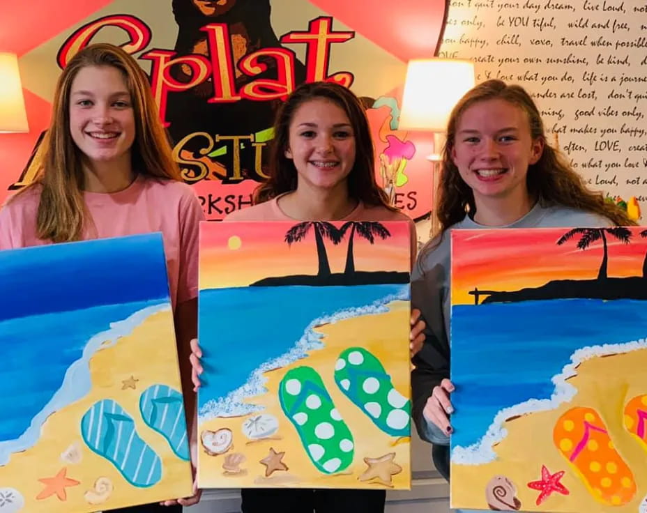 a group of girls holding up artwork