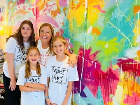 a group of girls posing in front of a wall with graffiti