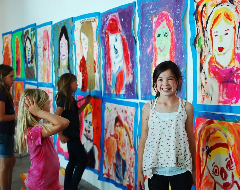 a group of children standing in front of a wall with art