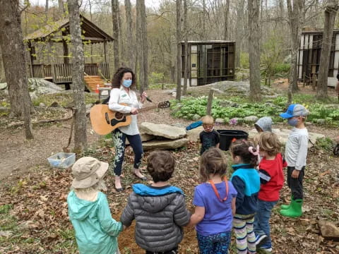 a person playing guitar in front of a group of children