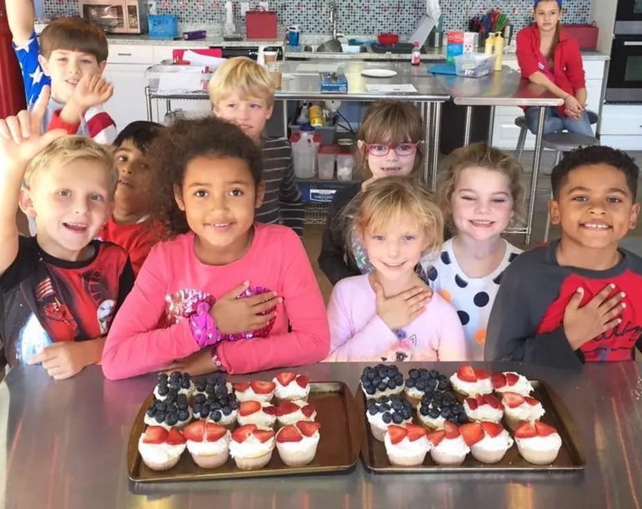 a group of kids posing for a picture with cupcakes
