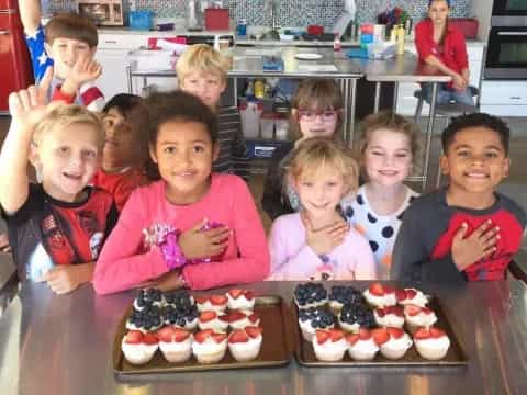 a group of kids posing for a picture with cupcakes