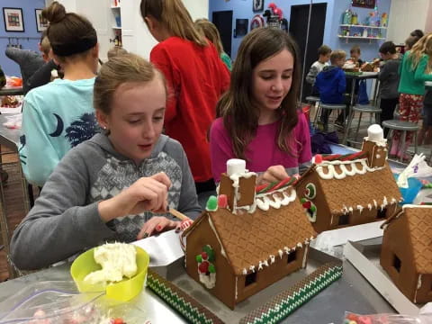 a group of people sitting at a table with gingerbread houses