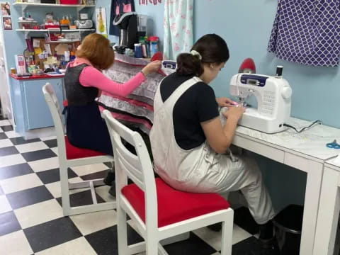 a group of people sitting at a desk with a sewing machine