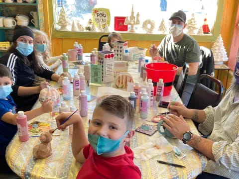 a group of people sitting around a table with a child in a mask