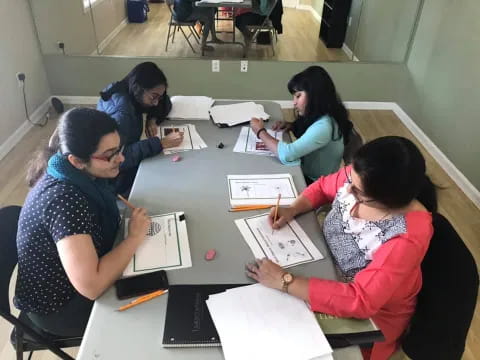a group of women sitting around a table writing on paper
