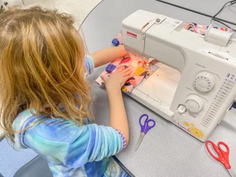 a young girl playing with a sewing machine