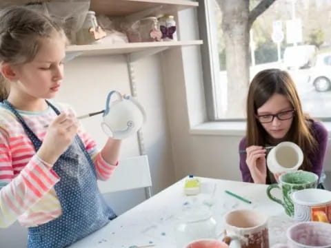 a young girl and a young girl sitting at a table with coffee cups