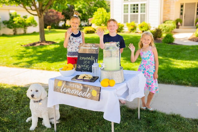 a group of kids standing around a table with food and drinks