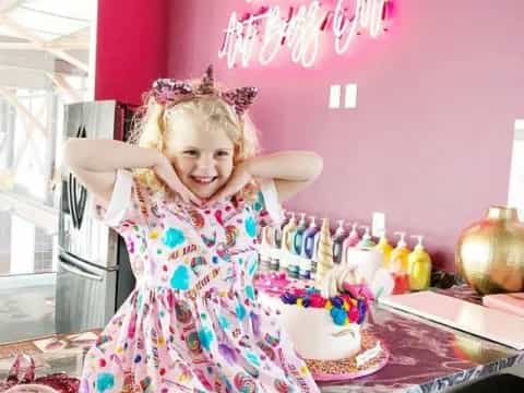 a girl in a dress with a cake on a table
