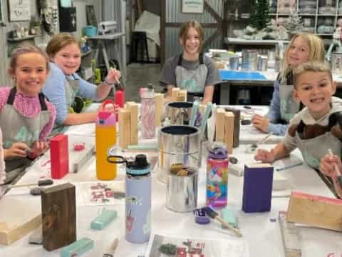 a group of girls sitting at a table with a blender and other objects