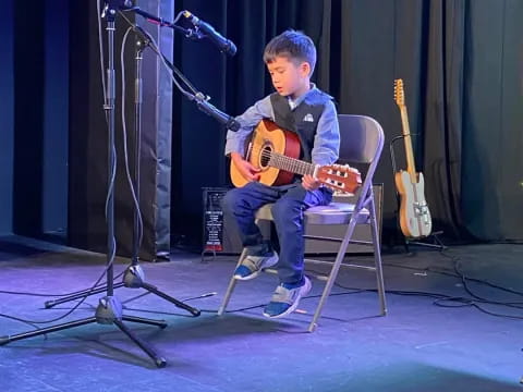 a boy playing a guitar on a stage